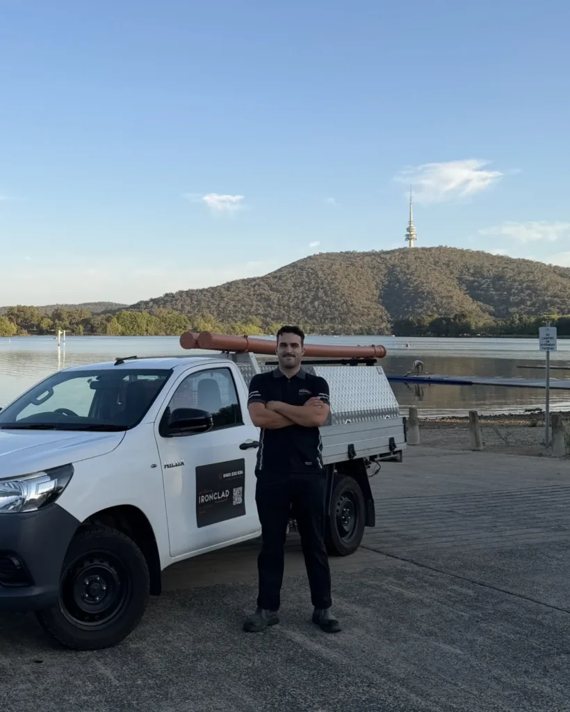 Ben Isaac standing beside the Ironclad Plumbing and Gas ute at Lake Burley Griffin in Canberra